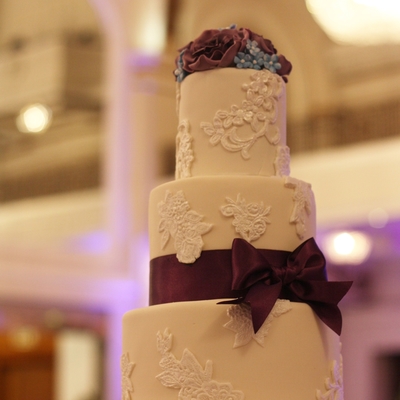 Ivory Cake With White Lace Applique Dark Purple Roses And Ribbon With Blue Filler Flowers Two Tiers Of Rich Chocolate And One Vanilla Bean... Ivory Cake With White Lace Applique Dark Purple Roses And Ribbon With Blue Filler Flowers Two Tiers Of Rich Chocolate And One Vanilla Bean...