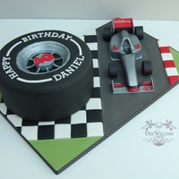 Formula One Cake Smooth, Formula One tyre cake with a modelled gum paste car on a themed decorated board