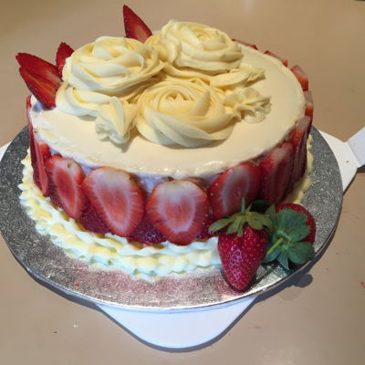 White Chocolate Ganache Piped Victoria Sponge Crumb Coated Sides To Which Slices Of Strawberry Stuck Around Its Outside Walls. White Chocolate Ganache Piped Victoria Sponge Crumb Coated Sides To Which Slices Of Strawberry Stuck Around Its Outside Walls.