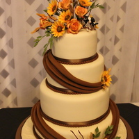 Stacey white chocolate fondant,,gum paste flowers- mini sunflowers,roses, wheat ,and alfalfa sprigs. bride wanted 2 cows on top, die hard farmers...