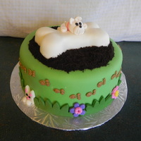 Katie's Puppy Cake MMF covered cake. Gum paste added to fondant for dog. Bone made of RCT. Dirt is crushed oreo's. BC paw prints.