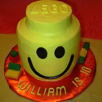 Lego Head 3 6" rounds stacked and covered in yellow buttercream. 4" round on top for 'nub'. Legos on the board are chocolate...