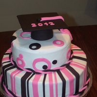 Pink And Black Grad Cake Buttercream iced with fondant strips and circles. Fondant graduation cap on top. 12" and 8" round cakes