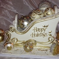 Christmas Sleigh In White Chocolate White Chocolate Christmas Sleigh and Ornaments. Decorated with Gold and Silver Luster High Lighter. Also Gold and Silver Wilton Sugars.