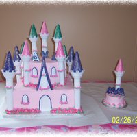 Ava's Castle Castle cake for a 1st birthday. Butter cream icing, MMF used on the spres & around windows. Flowers are buttercream around cake, and...