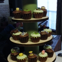 Anniversary Cupcake Tower Top tier has wedding photo on one side and current photo on the other side. The cupcakes have candy/fondant items on top of them that are...