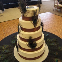 Peacock Feather Delight Light ivory buttercream frosting, satin ribbon and peacock feathers.
