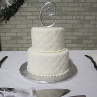 Quilted 2 tier round, white almond cake with white fondant, quilted pattern and fondant pearl border.
