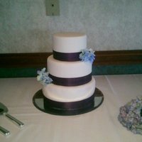 Blue Hydrangeas & Eggplant 10" banana cake w/custard filling. 8" & 6" fake tiers. Frosted in fondant w/fabric ribbon & silk hydrangeas.