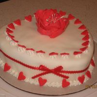 Sweetheart Cake Strawberry Buttercream Cake covered in fondant decorated with star shaped border covered with red fondant hearts and a fantasy flower in...