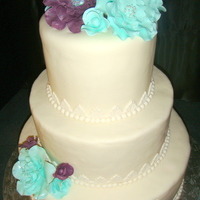 Wedding Cake For Riverboat Venue Three tiered, round wedding cake with gumpaste flowers in mint & plum colors. Made for a wedding on a riverboat.
