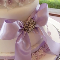 Lilac Flowers And Ribbon Wedding Cake Lilac themed wedding cake with flowers, ribbon and beadwork