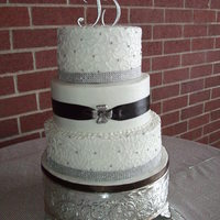 Cornelli Lace Wedding Buttercream frosting with cornelli lace on top and bottom tiers. Middle tier with real ribbon and brooche.