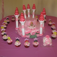 Pink Castle 2 tier cake with cupcakes and minicake carriage. princess and heads on cupcakes are made of fondant