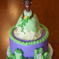 Princess And The Frog Six inch round cake with rkt Princess Tiana on top. Fondant frogs on side of the cake. Matching cupcakes with fondant crowns and lily pads...