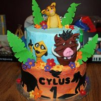 The Lion King Birthday cake with Lion King theme. Characters are fondant, flowers and leaves are gumpaste. Bottom tier is frosted with yellow orange...