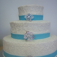 White/teal 3 Tier Wedding Cake vanilla cake iced with buttercream, a teal fondant border, silver antique pins