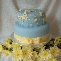 Flutter By Butterfly two tier blue and lemon fondant iced wedding cake with fondant butterflies and hand made ribbon with bow. the flowers around the bottom are...