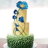Blue Poppy Cake Ombre green grass ruffles covered the bottom tier. Two yellow tiers brushed with gold dust and highlighted with bright blue poppies. I...