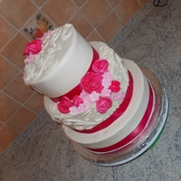 Pink Flowers Wedding Cake Three tier white cake with white buttercream. Pastillage roses and stephanotis are airbrushed. Buttercream scroll work at flower bunching....