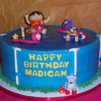Dora The Explorer Marble cake, vanilla buttercream, water is made with tinted piping gel. fondant/gumpaste figures.