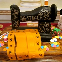 Singer Sewing Machine The sewing machine is RKT covered in black fondant and hand painted with gold pearl dust and vodka. The table is chocolate cake with a...