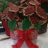 Poinsettia cake base with candy cane dirt and sugar cookie poinsettia flowers.