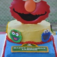 Elmo Elmo is a chocolate plaque and the other characters are made from color flow. The sign is a butter cream transfer.