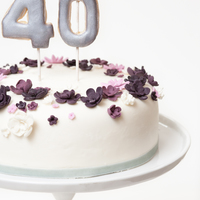 Violet Floral Crown Inspired 40Th Birthday Cake Single tier cake covered with marshmallow fondant and decorated with simple fondant flowers in hues of purple and white. Finished with...