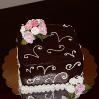 Chocolate Anniversary Cake Anniversary cake covered in dark chocolate ganache with white chocolate scrollwork. Gumpaste roses and carnations.