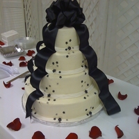 4-Tier French Vanilla Buttercream Smooth buttercream accented with black fondant flowers and subtle piping.