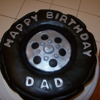 Tire Birthday Cake Black fondant on vanilla cake. SMBC filling and ABC for the icing. The center piece and letters are a gumpaste and fondant mix with silver...