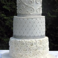 3 Tier All White Wedding Cake Decorated With Buttercream Rosettes Quilting And Scrolling And Accented With Silver Pearls And Glam Ribbon 3-tier all-white wedding cake decorated with buttercream rosettes, quilting and scrolling, and accented with silver pearls and glam ribbon...