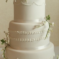 White, Piped Wedding Cake With Camelias Piped decorations on each cake tier. Sugar flowers include camelias, freesias, lily of the valley and hypericum berries.