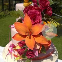 Flower Weddingcake 2 tier pink weddingcake with asiatic lily's, yellow fresia, darkpink roses and cattleya orchids.