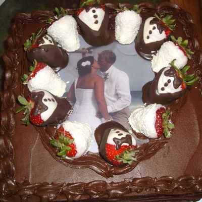 Edible Image Of Couple Surrounded By Dipped Strawberries On Top Of A Square Chocolate Cake With Chocolate Frosting