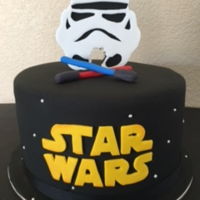 Star Wars Cake Star Wars logo with stars, lightsabers, and a stormtrooper topper.