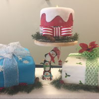 Christmas Hanukkah Top is a candle cake, bottom two cakes are presents. The center is a penguin cake stand made with fondant over an underlying cake structure...