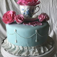 Tea Party Cake 5 layer vanilla bean cake, filling and ganache under pale blue fondant. Topped with a dainty tea cup and saucer with hand made roses and a...