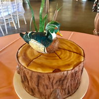 Wood Duck On Tree Stump Wood duck carved out of cake and covered in modeling chocolate. Then hand painted with petal dusts. Wafer paper grass, fondant cat tails,...